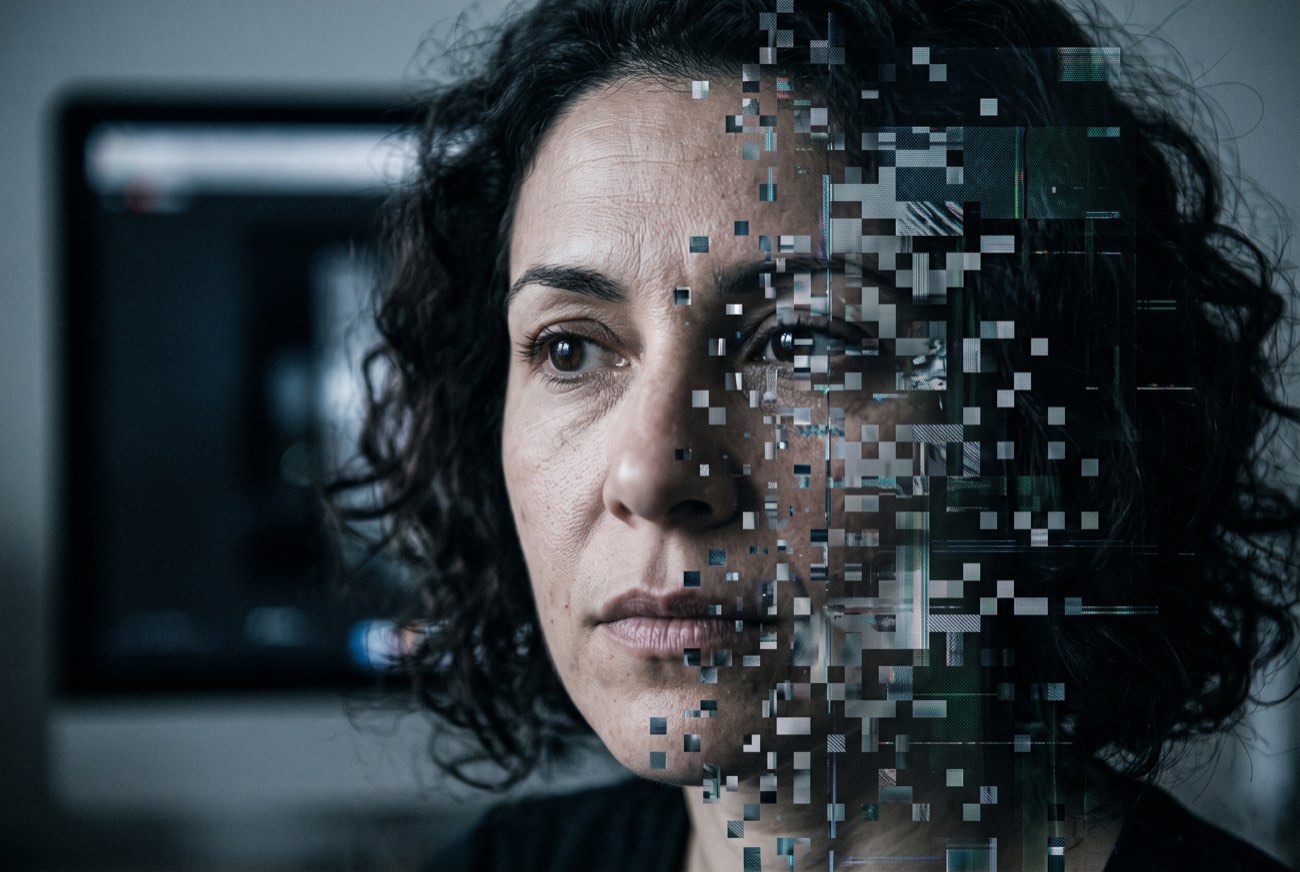 Volto umano scomposto in una griglia di pixel su uno schermo scuro